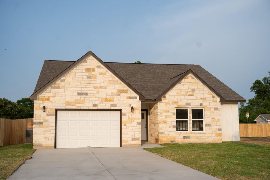French country style house featuring roof with shingles, concrete driveway, an attached garage, and stone siding