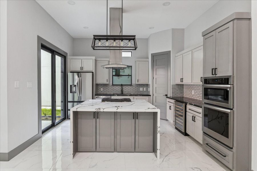 A light-filled kitchen with clean lines showcases a waterfall island, stainless appliances, and double ovens for everyday ease. The vent hood and brick-pattern backsplash create a striking focal point, complemented by under-cabinet lighting and a beverage cooler for added functionality. A light-filled kitchen with clean lines showcases a waterfall island, stainless appliances, and double ovens for everyday ease. The vent hood and brick-pattern backsplash create a striking focal point, complemented by under-cabinet lighting and a beverage cooler for added functionality.