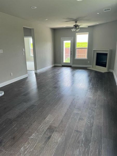 Unfurnished living room featuring ceiling fan and dark wood-type flooring