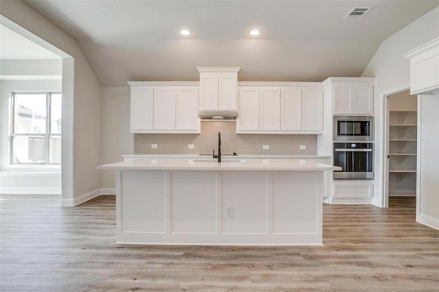 Kitchen with white cabinetry, sink, light hardwood / wood-style flooring, lofted ceiling, and appliances with stainless steel finishes