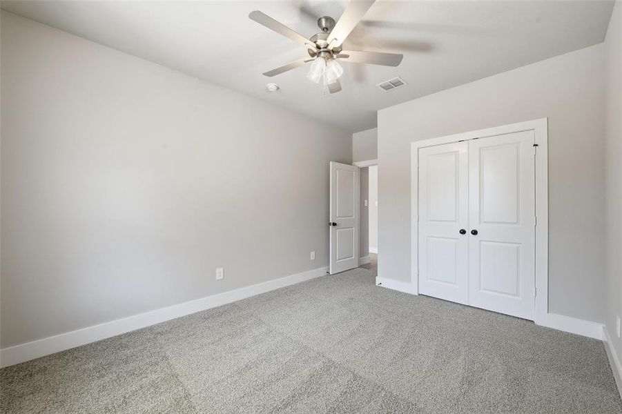 Unfurnished bedroom with carpet floors, a closet, and a ceiling fan Unfurnished bedroom with carpet floors, a closet, and a ceiling fan
