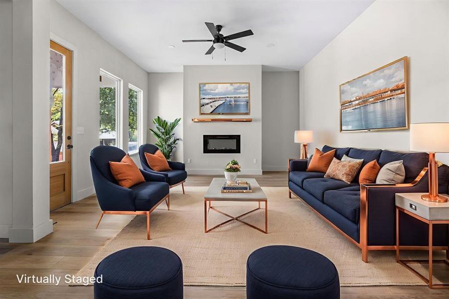 Living room featuring wood finished floors, a glass covered fireplace, a ceiling fan, and recessed lighting
