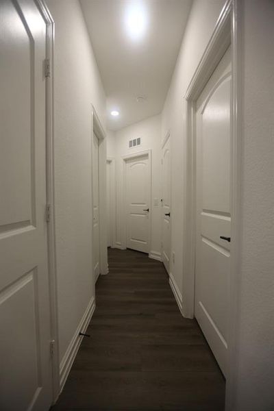 Hallway featuring wood-finish flooring, white paneled doors, recessed lighting, and crisp white baseboards