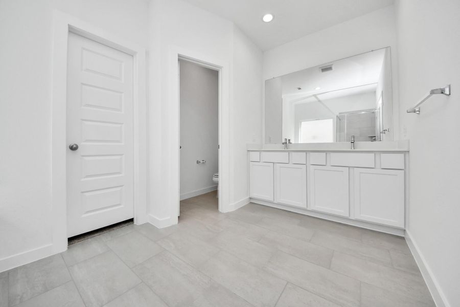 Indulge in a spa-like retreat within the confines of this primary bathroom. Delight in a spacious walk-in shower enveloped in stylish tile surround, unwind in a separate garden tub adorned with custom detailing. Sample photo of completed home with similar floor plan. Actual colors and selections may vary.