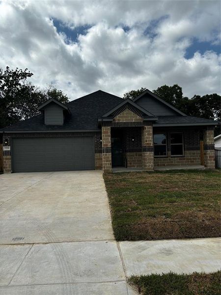 View of front facade featuring a garage and a front lawn