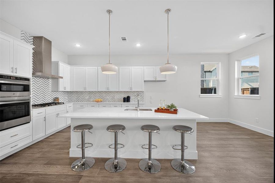 Kitchen featuring a breakfast bar area, tasteful backsplash, white cabinets, and recessed lighting Kitchen featuring a breakfast bar area, tasteful backsplash, white cabinets, and recessed lighting