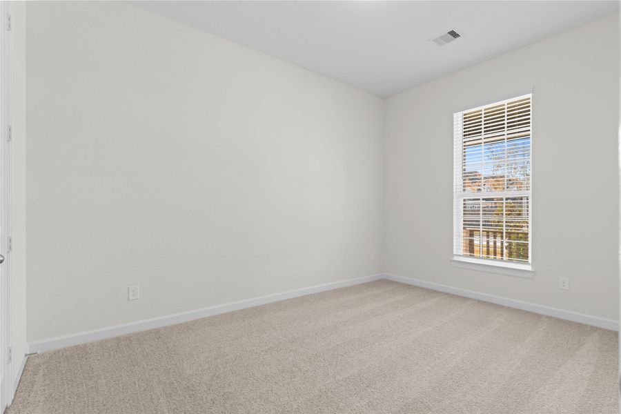 Another view of the secondary bedroom highlights its generous proportions and bright window, providing a peaceful and private space that feels open yet cozy, ideal for a bedroom, hobby room, or quiet reading nook.
