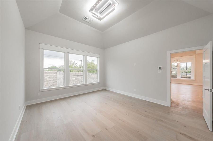 Empty room featuring light wood finished floors and a chandelier
