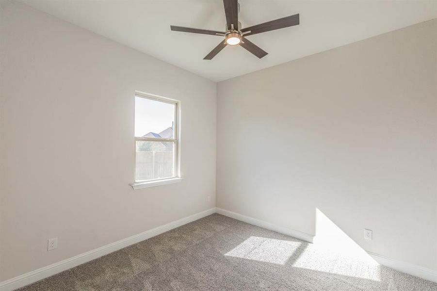 Carpeted spare room featuring ceiling fan