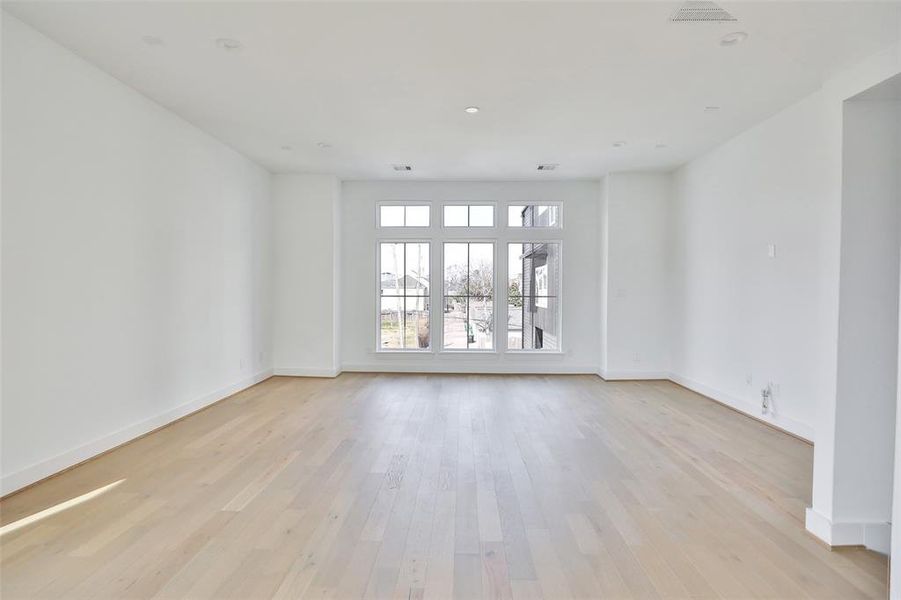 Soaring ceilings are bathed in natural light from the floor-to-ceiling windows. Imagine your sofa and TV in this inviting living room, creating the perfect space for relaxation.