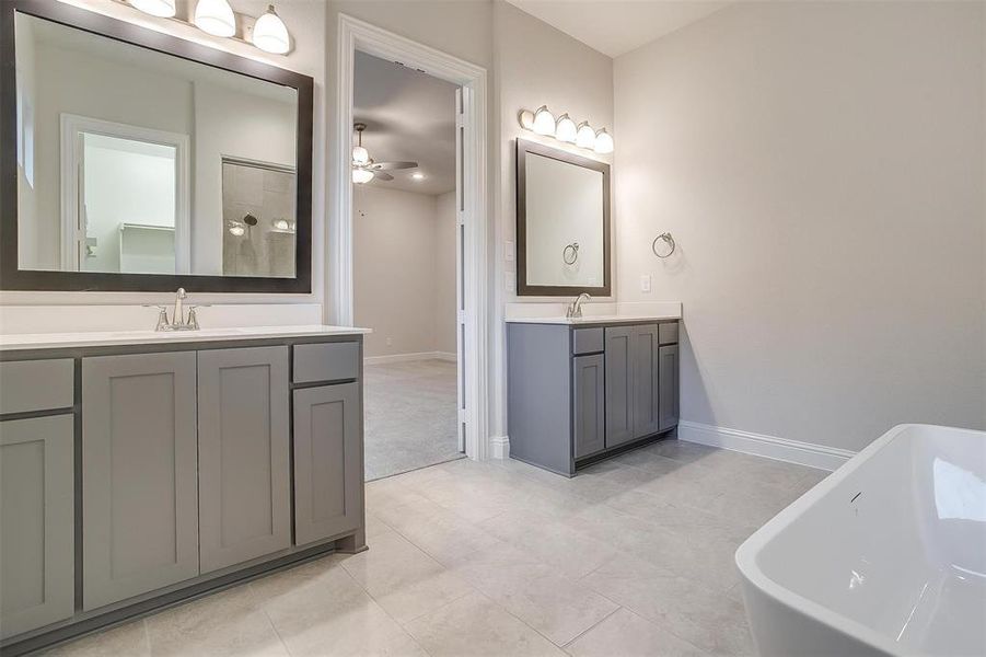 Bathroom with ceiling fan, double vanity, tile patterned flooring, and a bathtub