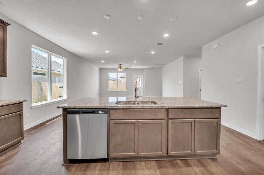 Kitchen featuring recessed lighting, stainless steel dishwasher, an island with sink, light stone counters, and light wood finished floors Kitchen featuring recessed lighting, stainless steel dishwasher, an island with sink, light stone counters, and light wood finished floors