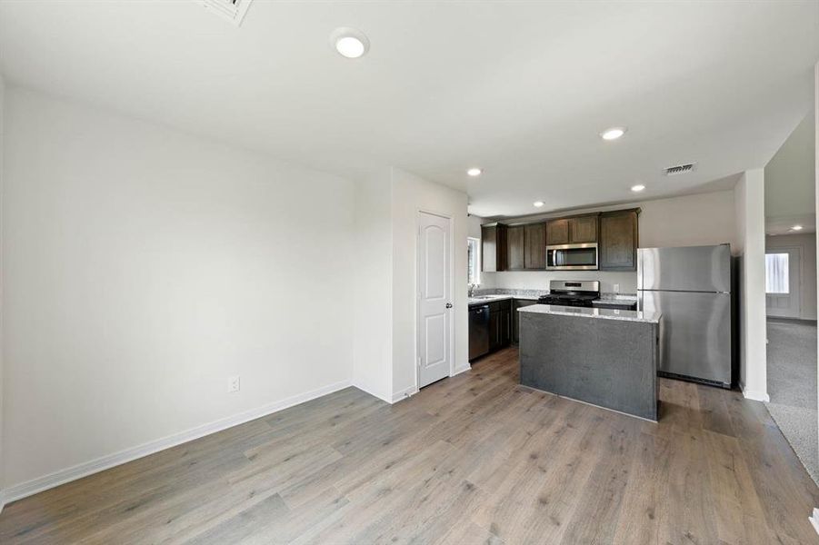 Kitchen featuring appliances with stainless steel finishes, dark brown cabinets, a center island, recessed lighting, and open floor plan