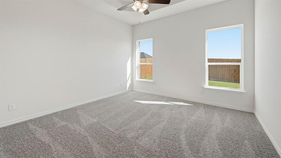 Room featuring light gray carpeting, two windows, a ceiling fan, and white painted walls