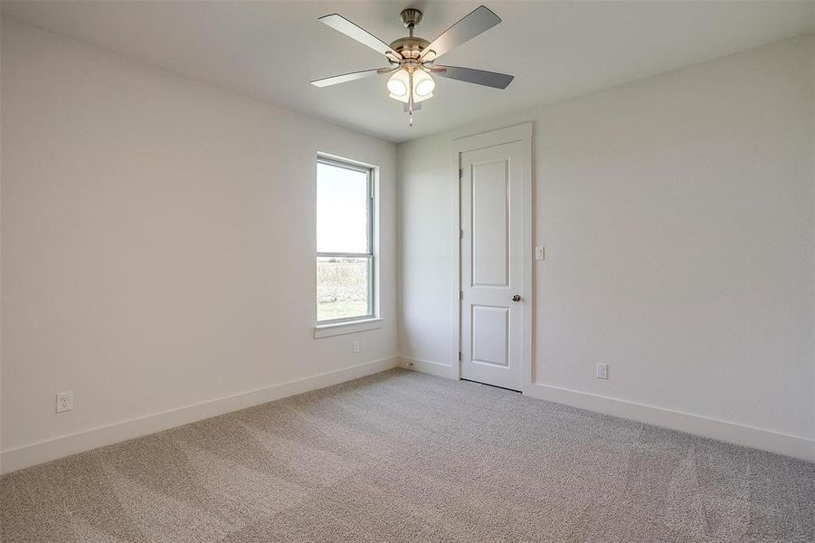 Carpeted spare room featuring ceiling fan