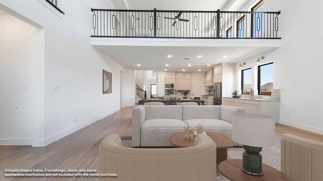 Living area featuring stairway, light wood-style flooring, a towering ceiling, radiator heating unit, and ceiling fan