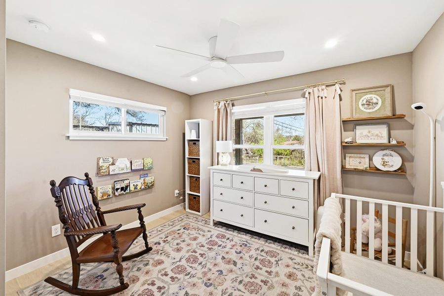Bedroom with multiple windows, a ceiling fan, a crib, light wood-style flooring, and recessed lighting