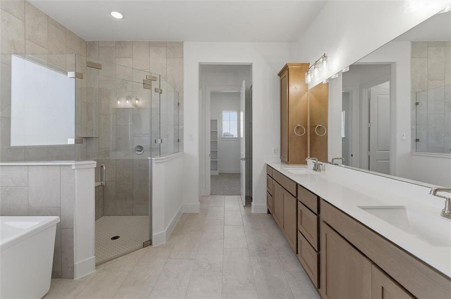 Spacious bathroom featuring a dual vanity with white countertops, light wood-finish cabinetry, and brushed nickel fixtures