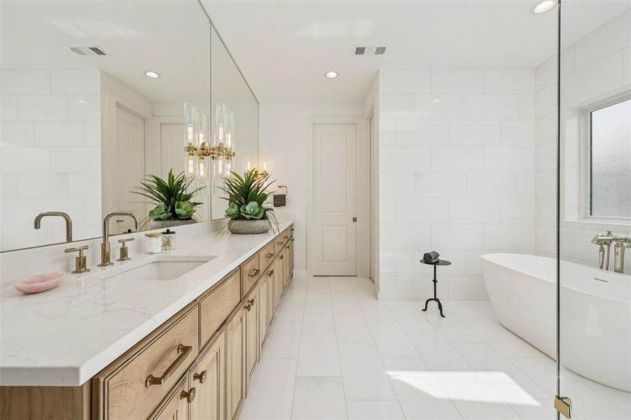 Spacious bathroom featuring a freestanding soaking tub, a dual vanity with a white countertop and natural wood-finish cabinetry, and a full-height mirror