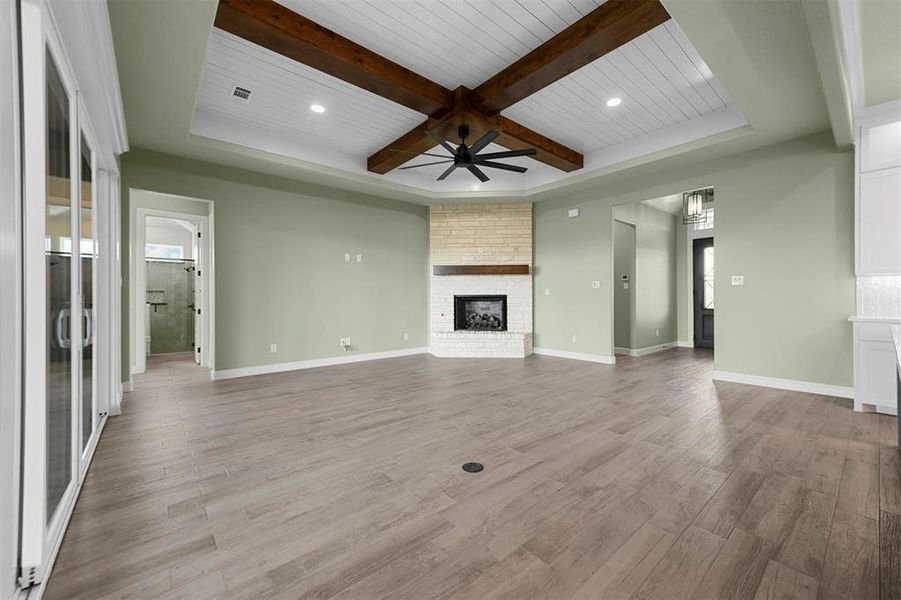 Unfurnished living room with ceiling fan, a brick fireplace, beamed ceiling, light hardwood / wood-style floors, and wood ceiling