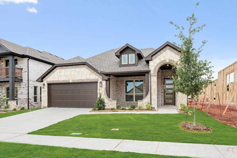Single-story home with stone and brick exterior, two-car garage, arched entry, and green front lawn.