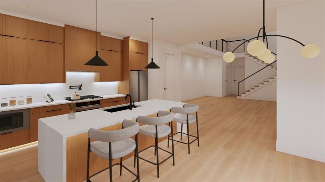 Kitchen featuring a center island with sink, a kitchen breakfast bar, pendant lighting, and modern cabinets