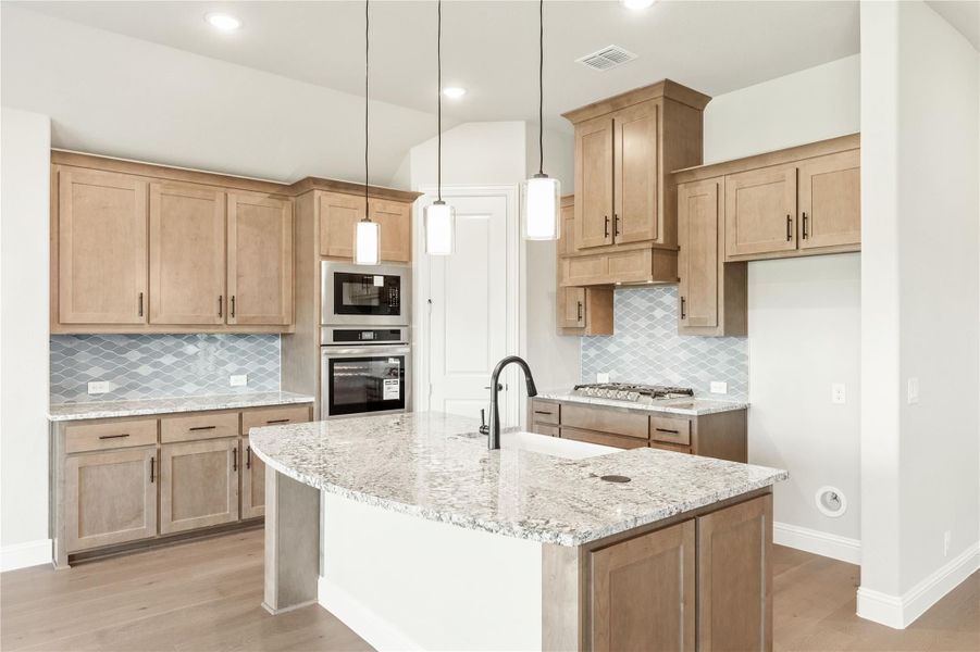 Kitchen with light wood cabinets, granite island, pendant lights, and blue tile backsplash Kitchen with light wood cabinets, granite island, pendant lights, and blue tile backsplash