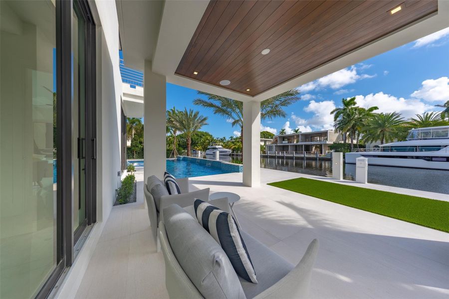 On the first floor, a guest room opens to a covered patio with breathtaking waterfront views,