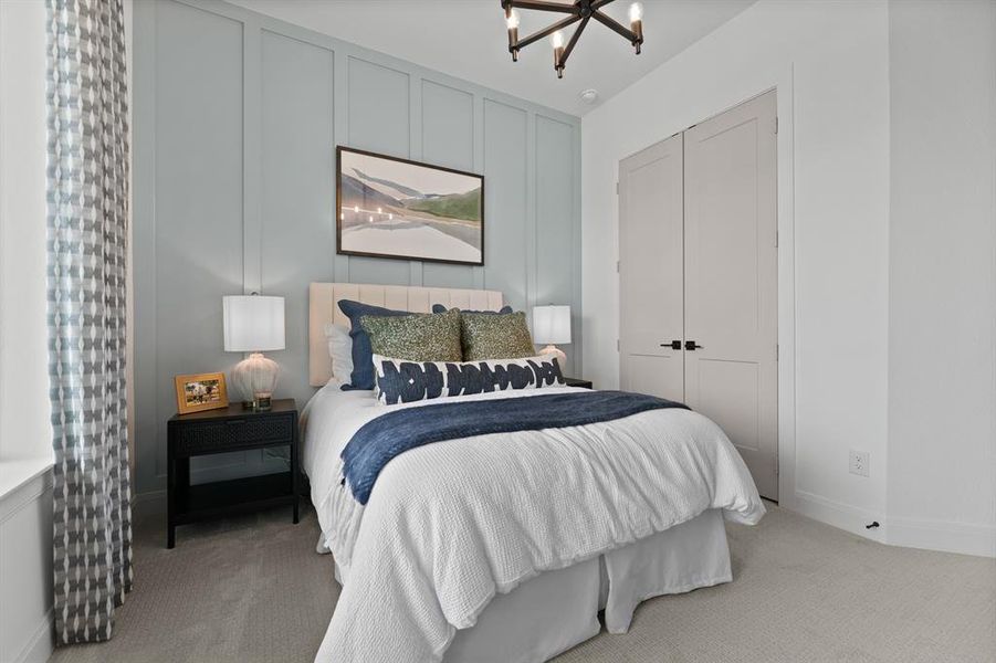 Bedroom featuring a decorative wall, light carpet, suspended lighting, and a closet Bedroom featuring a decorative wall, light carpet, suspended lighting, and a closet