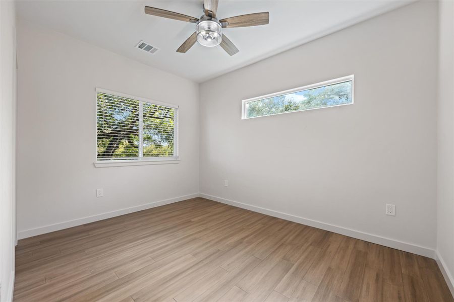 Empty room featuring healthy amount of natural light, wood finished floors, and ceiling fan