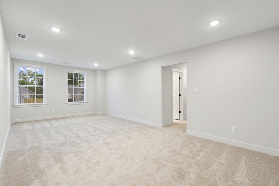 Spacious room featuring neutral carpeting, recessed lighting, and two double-hung windows with grid patterns Spacious room featuring neutral carpeting, recessed lighting, and two double-hung windows with grid patterns