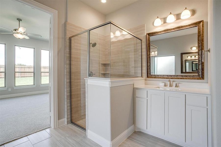 Bathroom featuring tile patterned floors, a shower with shower door, vanity, and ceiling fan