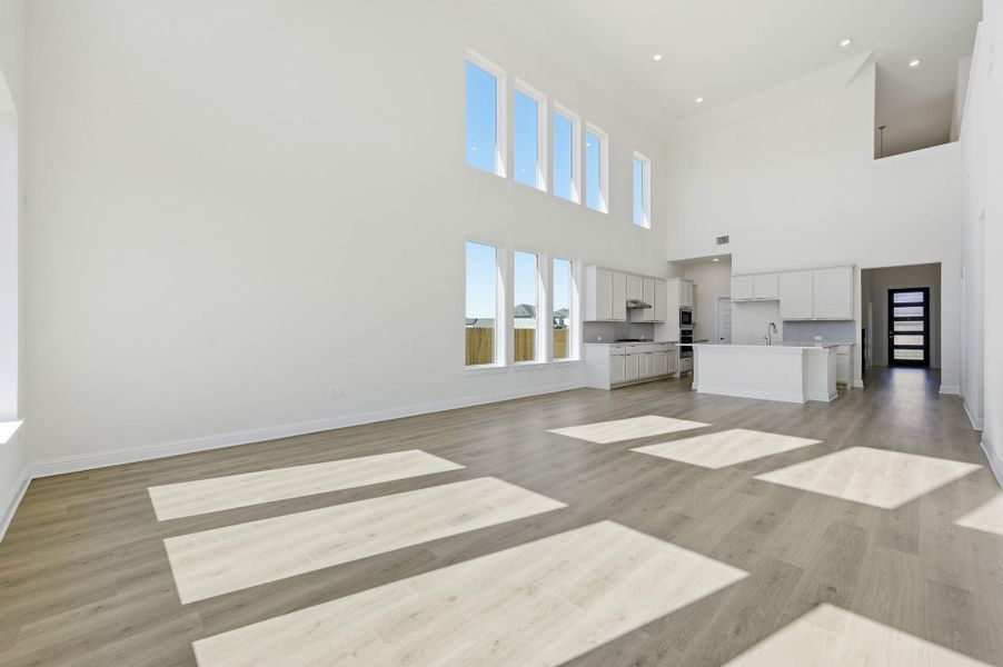 Unfurnished living room featuring light wood-style floors and a high ceiling