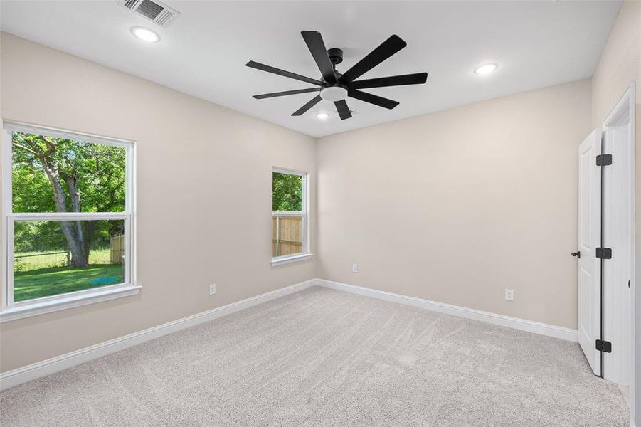 Room featuring light beige walls, two windows, and light-toned carpet flooring