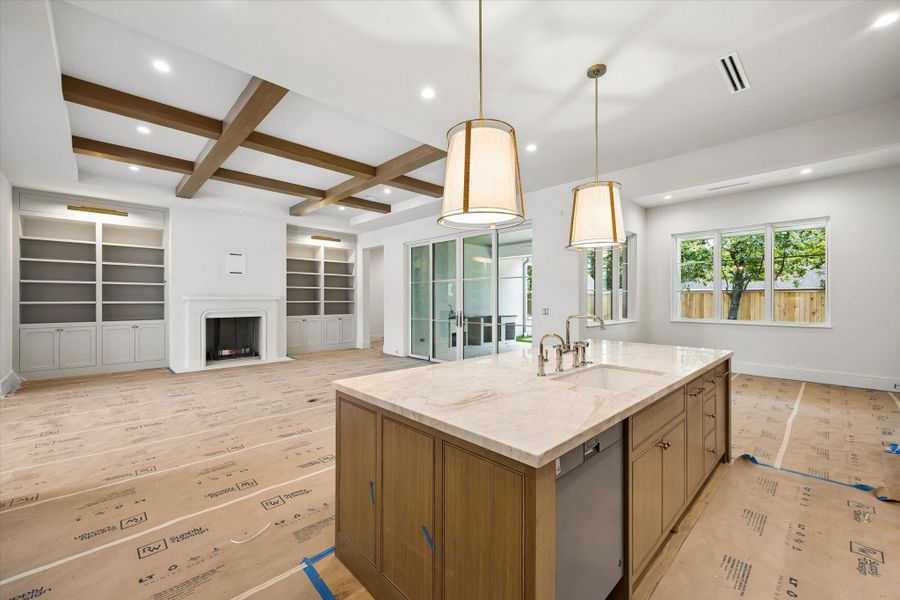 The kitchen island features a Quartzite countertop, white oak details, and plenty of storage! The kitchen vent-hood is completed with a plaster finish.