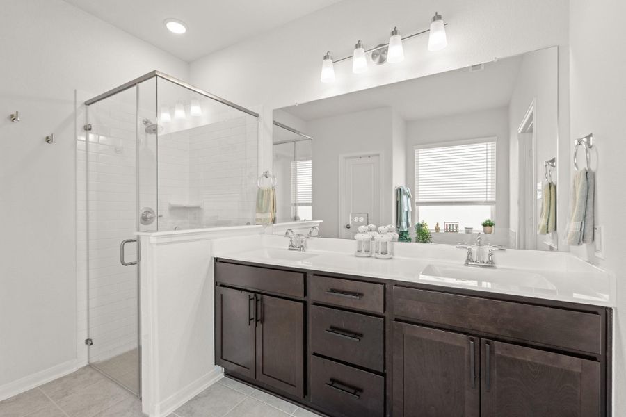 You'll love getting ready in this light and bright primary bathroom! The primary bathroom includes a large vanity with dual sinks, quartz counters, large mirror, and wood cabinets.