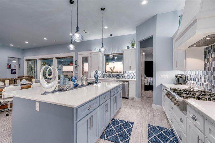 Kitchen featuring white cabinets, stainless steel appliances, hanging light fixtures, decorative backsplash, and recessed lighting