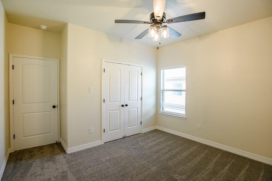 Unfurnished bedroom with dark colored carpet, a closet, and ceiling fan Unfurnished bedroom with dark colored carpet, a closet, and ceiling fan