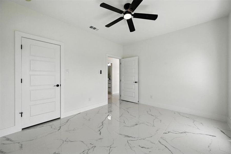 Unfurnished bedroom featuring marble finish floors and a ceiling fan