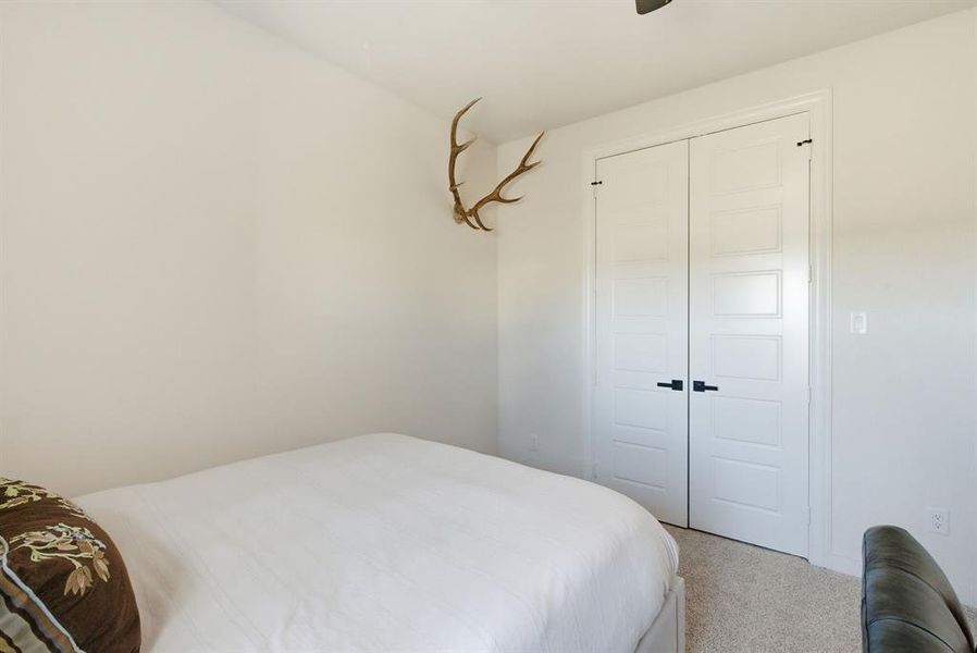 Carpeted bedroom featuring a closet and ceiling fan