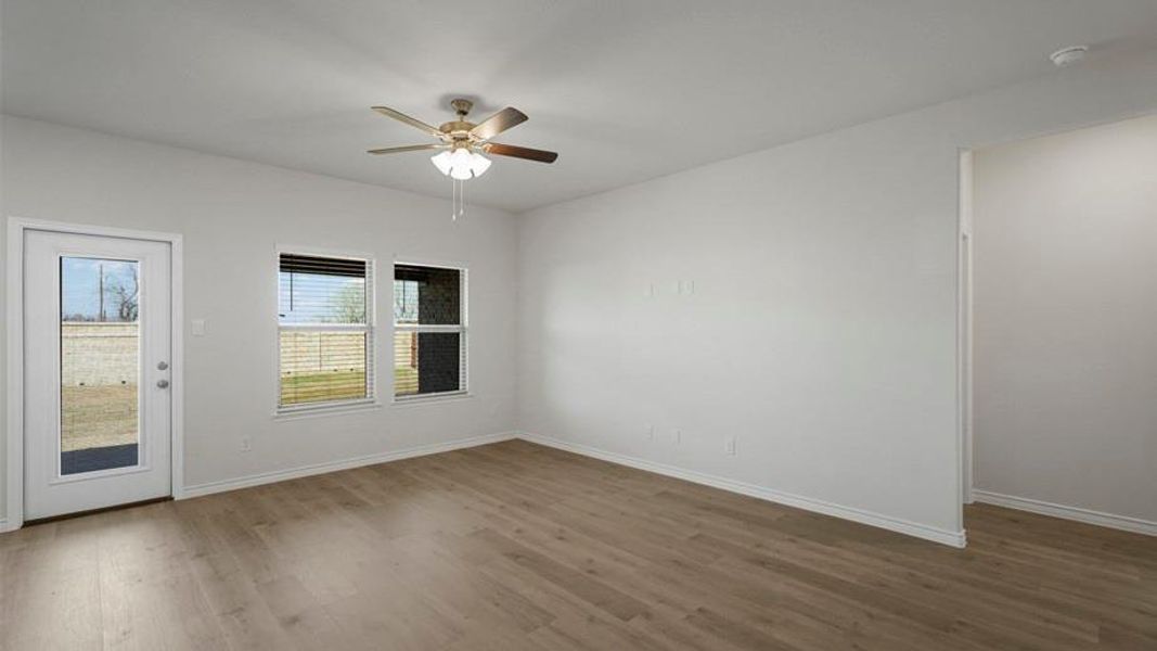 Spacious room featuring wood-finish flooring, light-toned walls, and a ceiling fan with integrated lighting