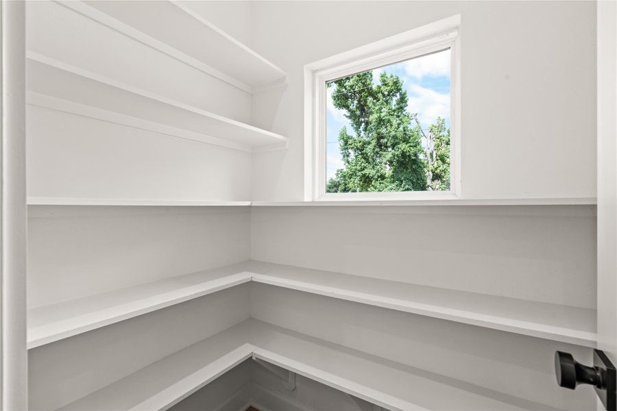 Bright, walk-in pantry featuring wrapped built-in shelving and a large window looking out at mature trees. Bright, walk-in pantry featuring wrapped built-in shelving and a large window looking out at mature trees.