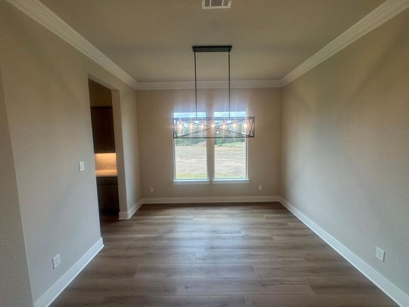 Dedicated room featuring wood-finish flooring, a modern linear chandelier, and dual windows