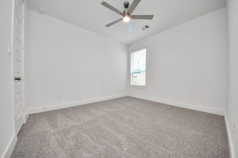 Secondary bedroom features plush carpeting, large windows that let in plenty of natural light, bright paint, and spacious closets.