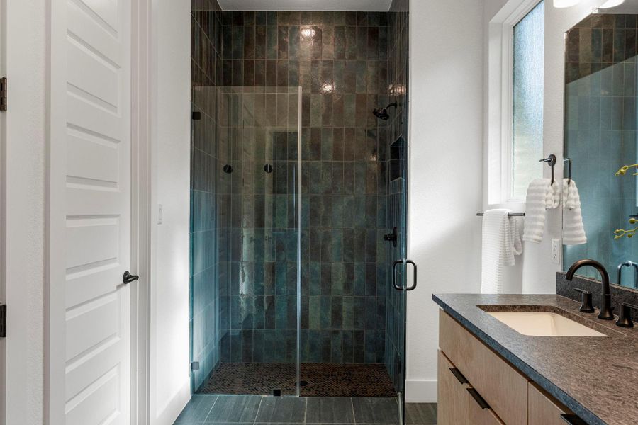 A sleek, contemporary shower with deep-toned tilework anchors this well-appointed bathroom.