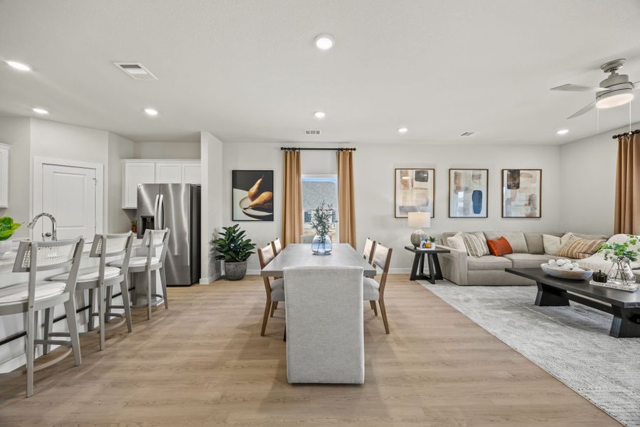 A large living room with a wood floor and a large dining table. A large living room with a wood floor and a large dining table.