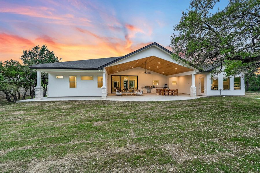 Rear view of property featuring an outdoor living space, a yard, a patio, stucco siding, and a ceiling fan