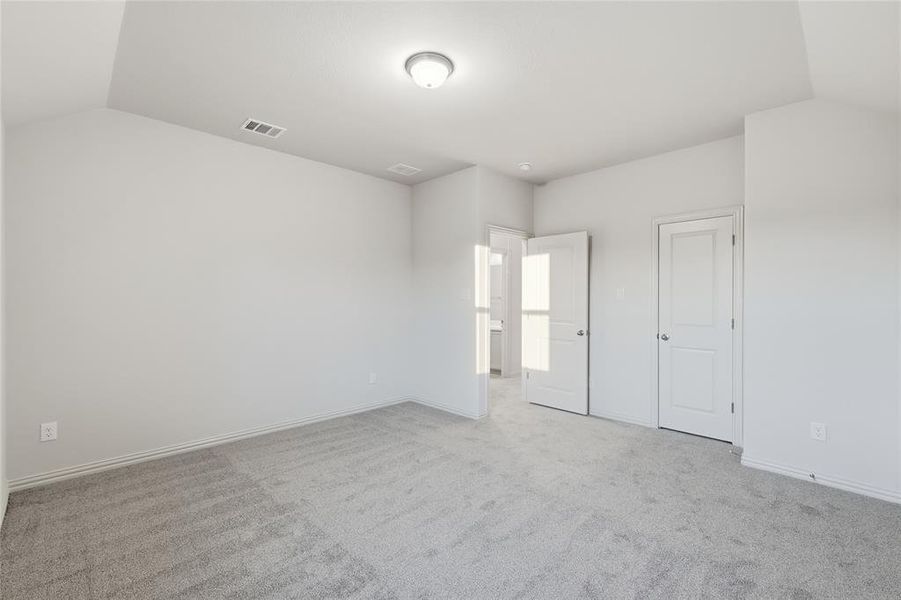 Unfurnished bedroom featuring light colored carpet and vaulted ceiling