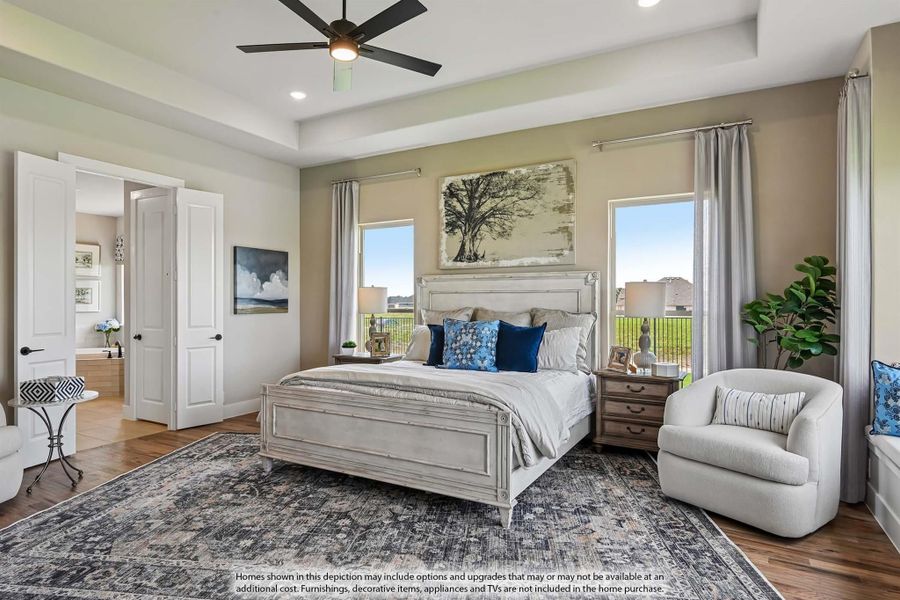 Master bedroom with tray ceiling, ceiling fan, hardwood floors, and large windows with natural light Master bedroom with tray ceiling, ceiling fan, hardwood floors, and large windows with natural light