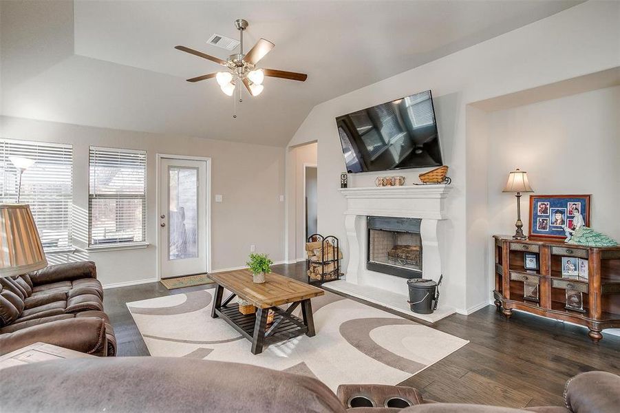 Living room with dark hardwood / wood-style flooring, ceiling fan, and lofted ceiling